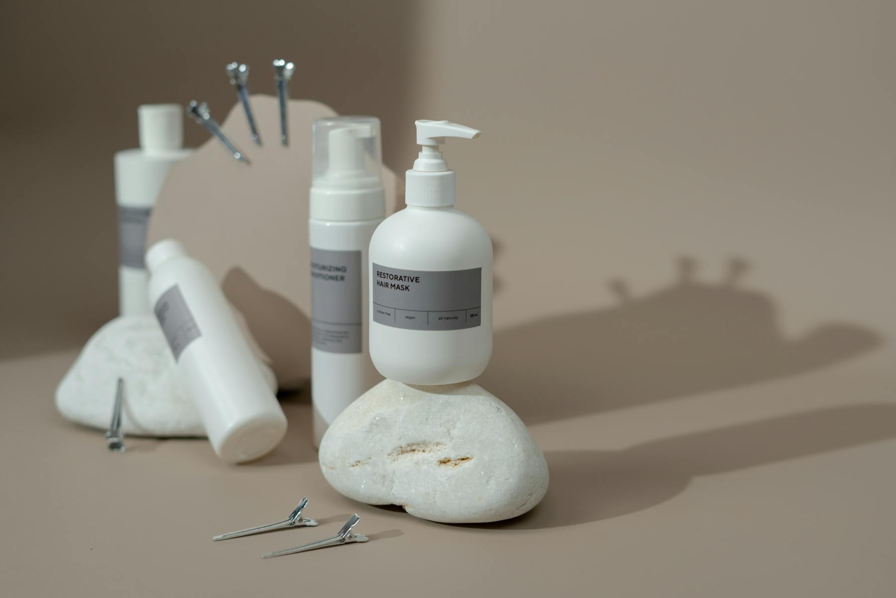 Hair care bottles and styling tools arranged on a stone surface.