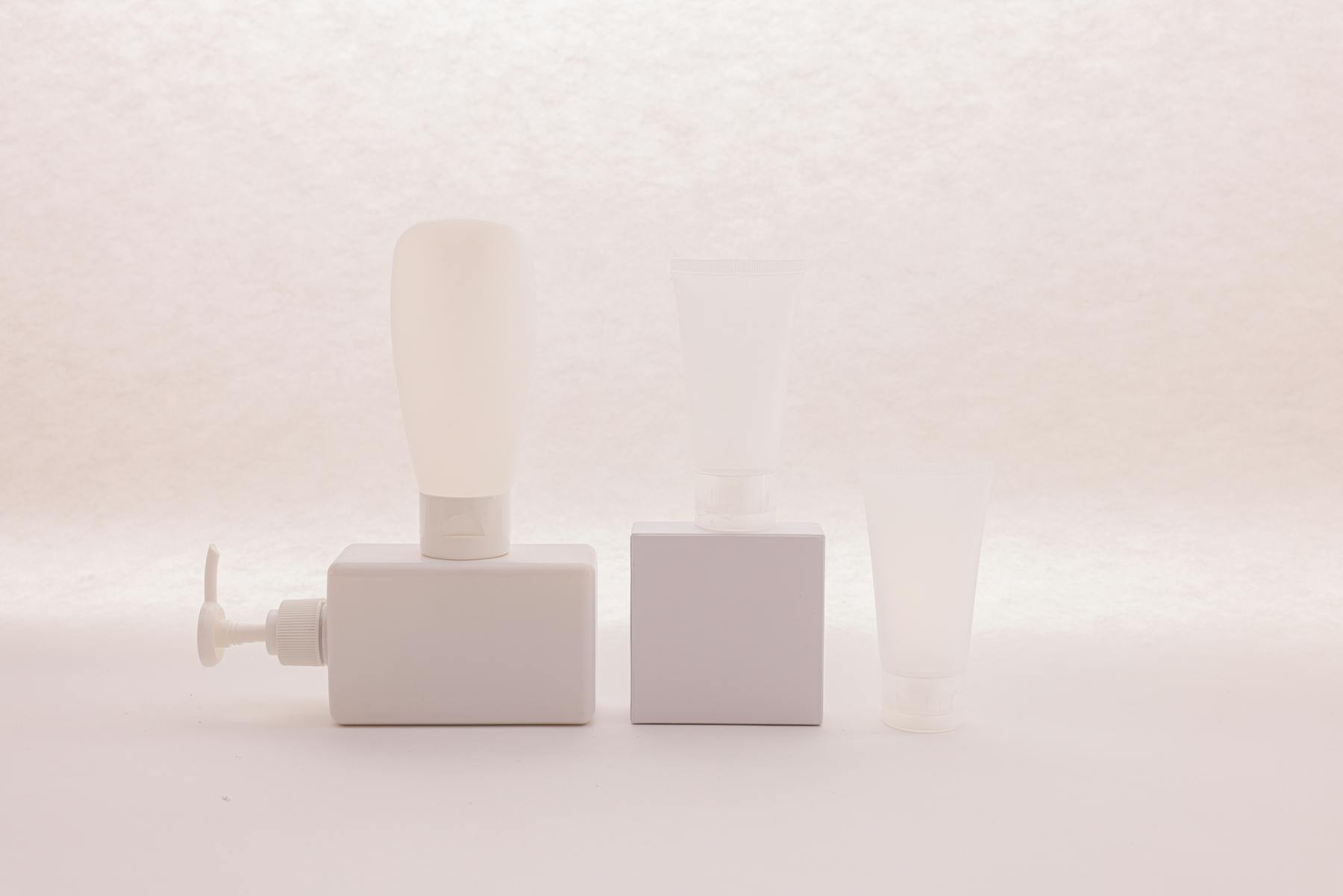 Unbranded beauty product containers arranged against a pale background.